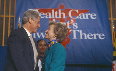 Bill and Hillary Clinton together in front of a health care sign